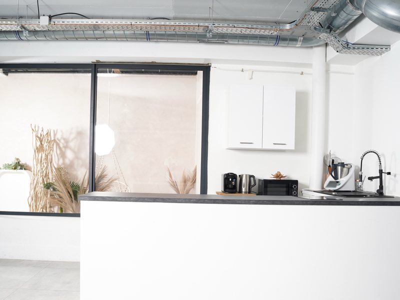 La cuisine équipée du Studio Urban : bar, café, bouilloire, micro-ondes, plaque et évier, ouverte sur le patio.